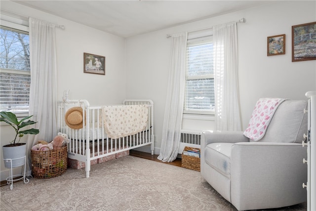 bedroom featuring a nursery area and radiator heating unit