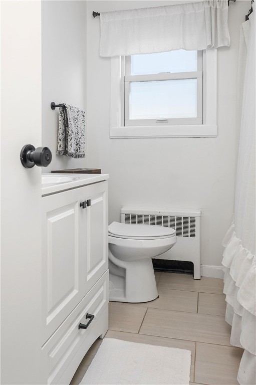 bathroom featuring tile patterned floors, radiator heating unit, toilet, and vanity