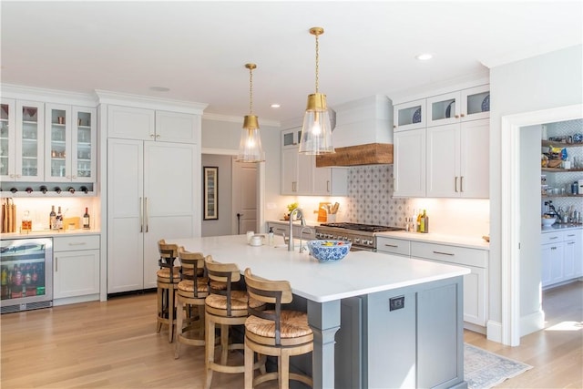 kitchen with custom exhaust hood, beverage cooler, and white cabinets