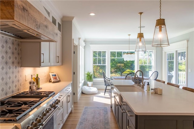 kitchen featuring premium range hood, pendant lighting, gray cabinetry, high end stainless steel range oven, and a kitchen island with sink