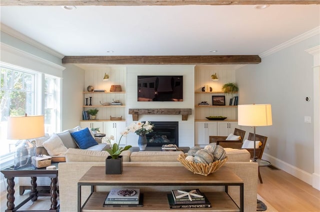 living room featuring a large fireplace, ornamental molding, beam ceiling, and light hardwood / wood-style flooring