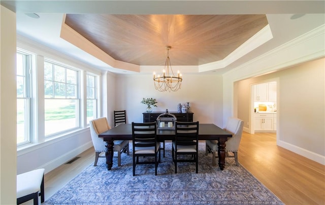 dining room featuring crown molding, hardwood / wood-style floors, a notable chandelier, and a tray ceiling