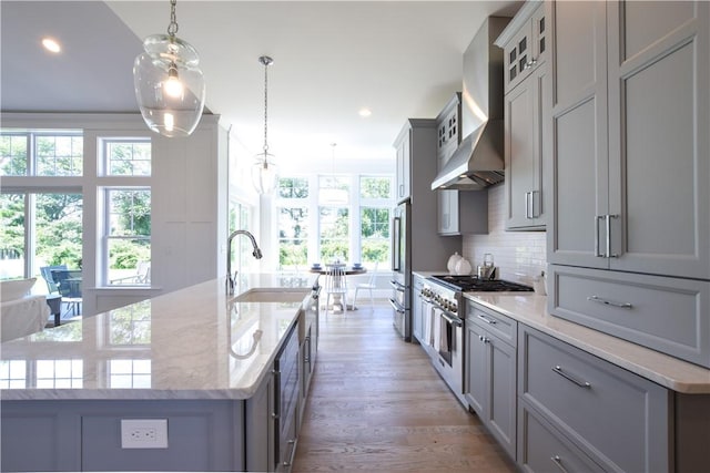 kitchen featuring a large island, pendant lighting, high end appliances, decorative backsplash, and wall chimney exhaust hood