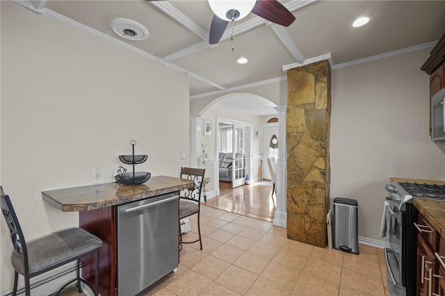 kitchen featuring crown molding, ceiling fan, appliances with stainless steel finishes, a kitchen breakfast bar, and decorative columns