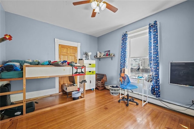 bedroom with ceiling fan, a baseboard radiator, and wood-type flooring