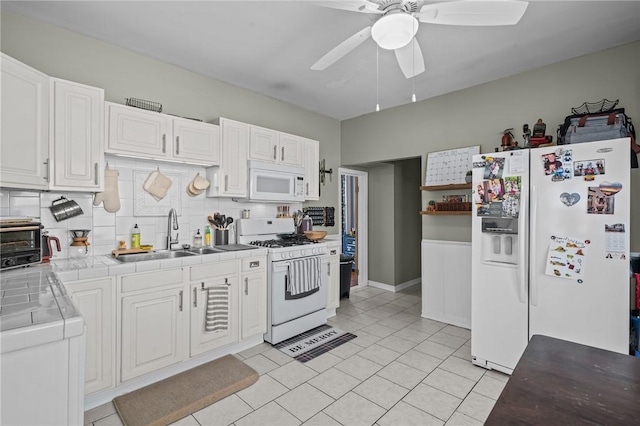 kitchen with sink, white appliances, tile countertops, and white cabinets