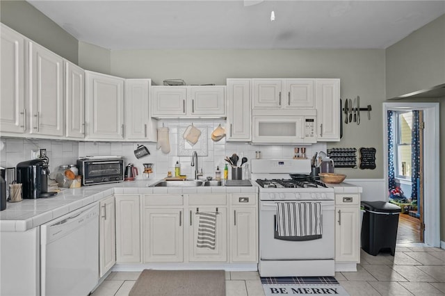 kitchen with white appliances, tile counters, and white cabinets