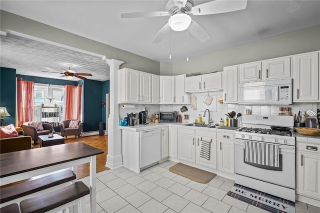 kitchen featuring sink, white cabinetry, ceiling fan, white appliances, and backsplash