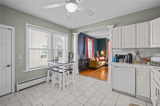 kitchen featuring light tile patterned floors, baseboard heating, white cabinetry, white dishwasher, and decorative backsplash