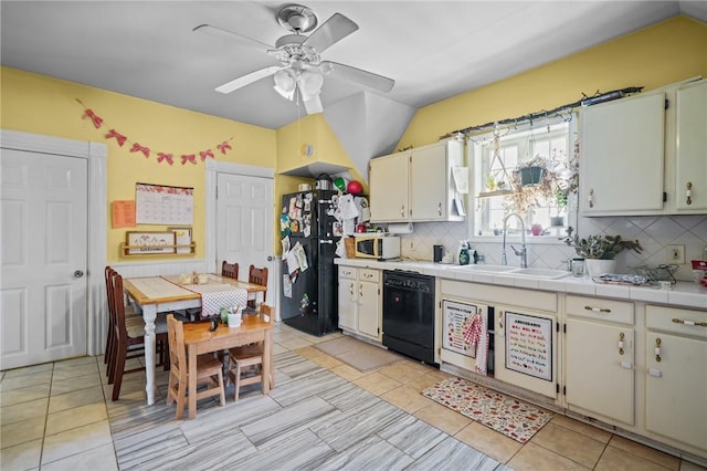 kitchen featuring sink, backsplash, tile counters, black appliances, and vaulted ceiling