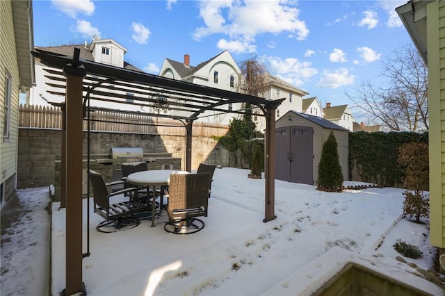 snow covered patio featuring a storage shed and a pergola