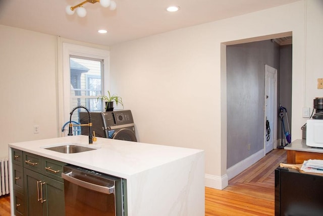 kitchen featuring a kitchen island with sink, sink, dishwasher, and light wood-type flooring