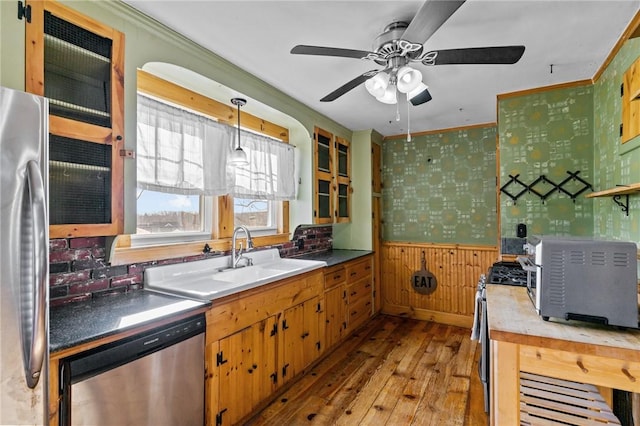 kitchen with sink, crown molding, pendant lighting, stainless steel appliances, and light hardwood / wood-style floors