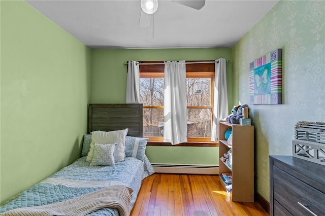 bedroom with light wood-type flooring, ceiling fan, and baseboard heating