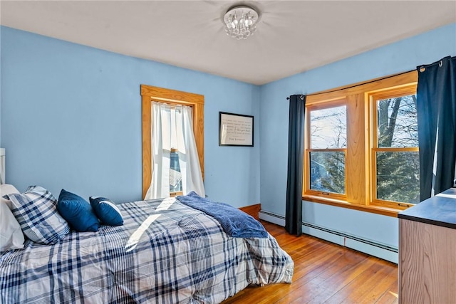 bedroom featuring a baseboard radiator, wood-type flooring, and a notable chandelier