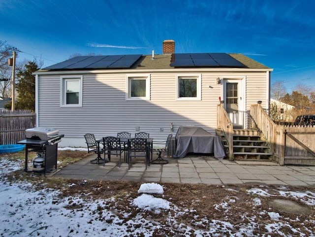 snow covered house featuring a patio and solar panels