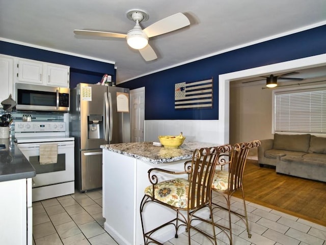 kitchen with white cabinets, light tile patterned floors, ceiling fan, kitchen peninsula, and stainless steel appliances