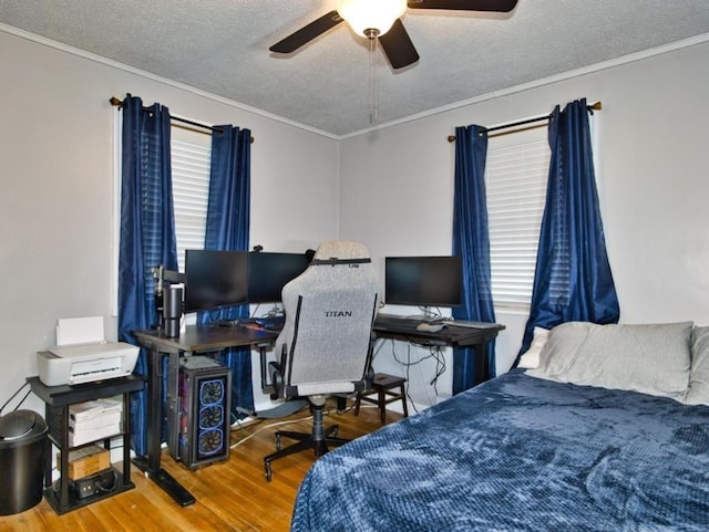 bedroom with multiple windows, wood-type flooring, ornamental molding, and a textured ceiling