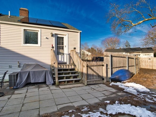 snow covered property with a patio and solar panels