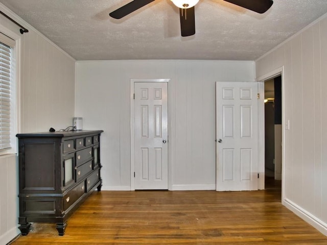 bedroom featuring dark hardwood / wood-style flooring, ceiling fan, ornamental molding, and a textured ceiling