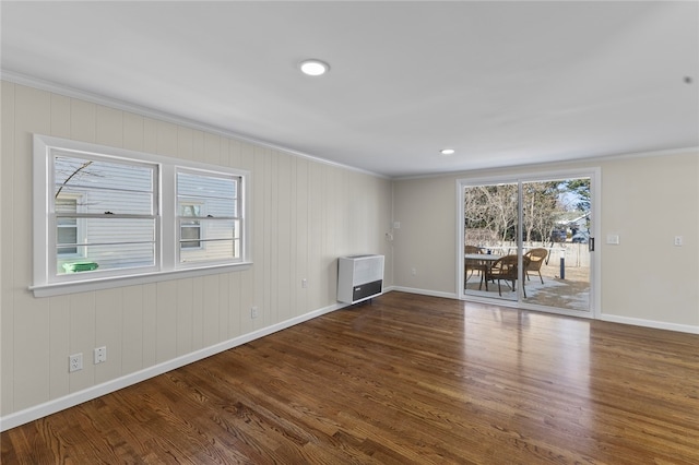 unfurnished living room featuring crown molding, dark hardwood / wood-style floors, and heating unit