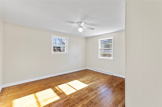 spare room with ceiling fan, a baseboard radiator, and wood-type flooring