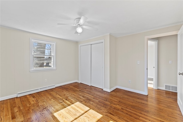 unfurnished bedroom with crown molding, hardwood / wood-style flooring, ceiling fan, a baseboard radiator, and a closet