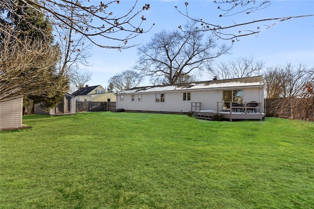 back of house featuring a wooden deck, a lawn, and a storage shed