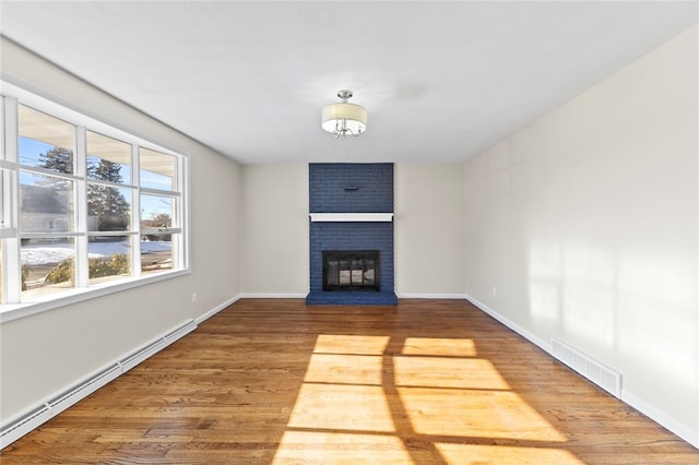 unfurnished living room with baseboard heating, a fireplace, and hardwood / wood-style floors