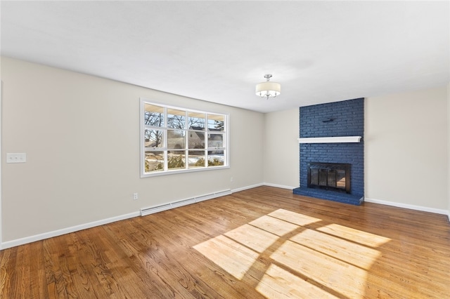 unfurnished living room featuring wood-type flooring, a brick fireplace, and baseboard heating