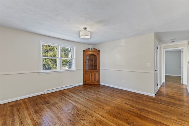 spare room with baseboard heating and wood-type flooring