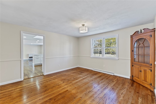 empty room with light hardwood / wood-style floors and a baseboard heating unit