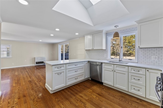 kitchen with sink, stainless steel appliances, white cabinets, decorative light fixtures, and kitchen peninsula