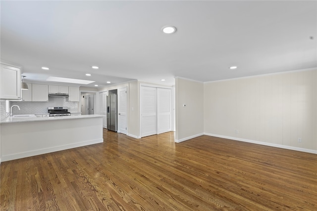 unfurnished living room featuring crown molding, dark hardwood / wood-style floors, and sink