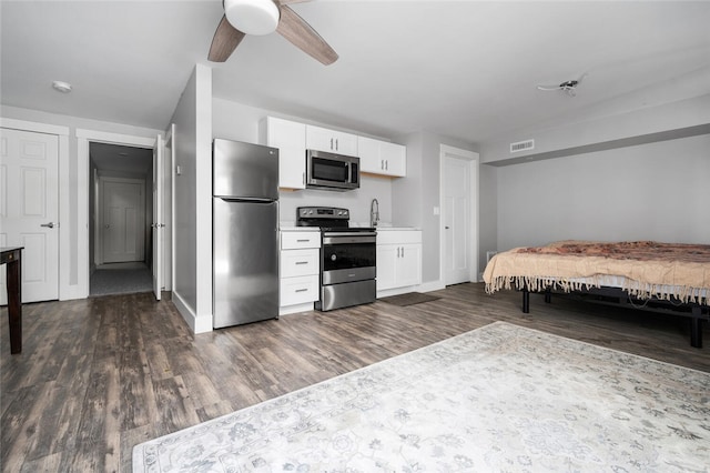 kitchen with sink, appliances with stainless steel finishes, dark hardwood / wood-style flooring, ceiling fan, and white cabinets