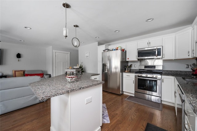 kitchen with stainless steel appliances, hanging light fixtures, dark hardwood / wood-style floors, and white cabinets