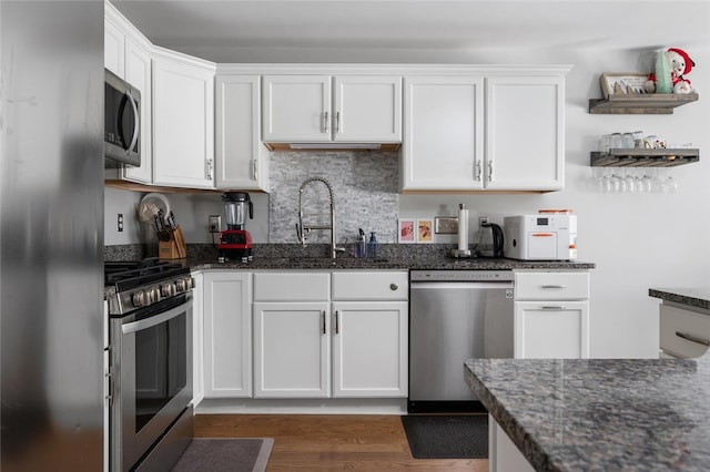 kitchen featuring stainless steel appliances, dark stone countertops, and white cabinets