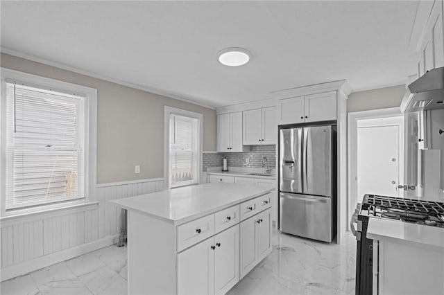 kitchen with sink, appliances with stainless steel finishes, backsplash, white cabinets, and a kitchen island