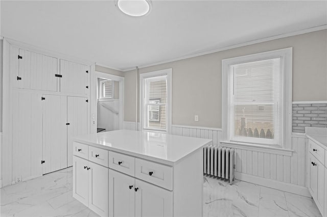 kitchen featuring white cabinetry, radiator heating unit, ornamental molding, and a kitchen island