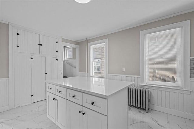 kitchen with white cabinetry, radiator heating unit, crown molding, and a center island