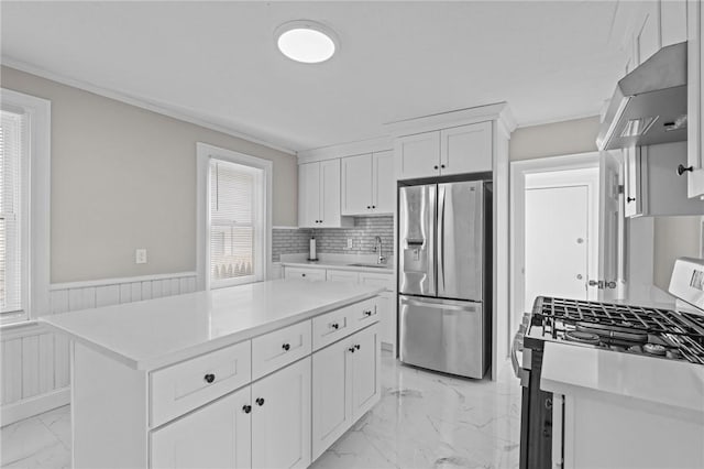 kitchen featuring sink, white cabinetry, crown molding, appliances with stainless steel finishes, and a kitchen island