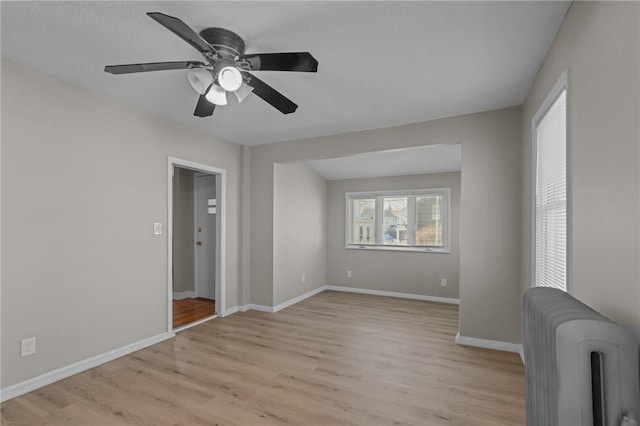 unfurnished room featuring radiator, ceiling fan, and light hardwood / wood-style flooring