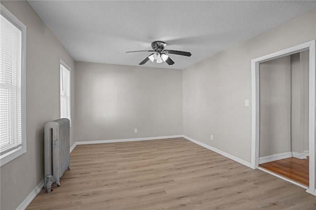 unfurnished bedroom featuring light hardwood / wood-style flooring, radiator heating unit, and ceiling fan