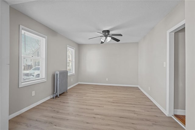 spare room featuring ceiling fan, radiator heating unit, a textured ceiling, and light hardwood / wood-style floors