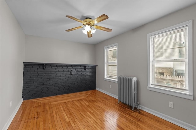 unfurnished room featuring radiator, ceiling fan, and light wood-type flooring