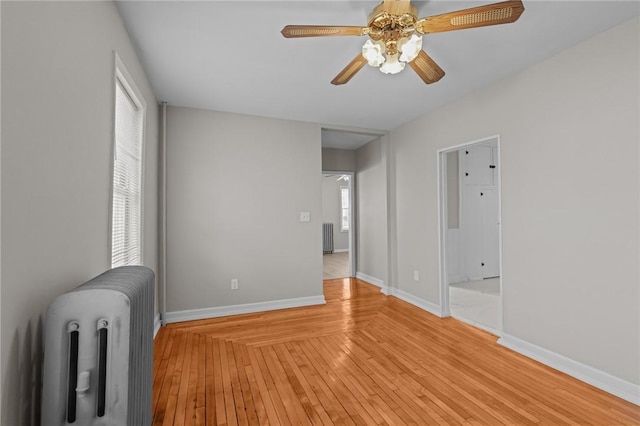 unfurnished room featuring radiator, light hardwood / wood-style floors, and ceiling fan