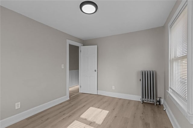 spare room featuring radiator heating unit and light hardwood / wood-style floors