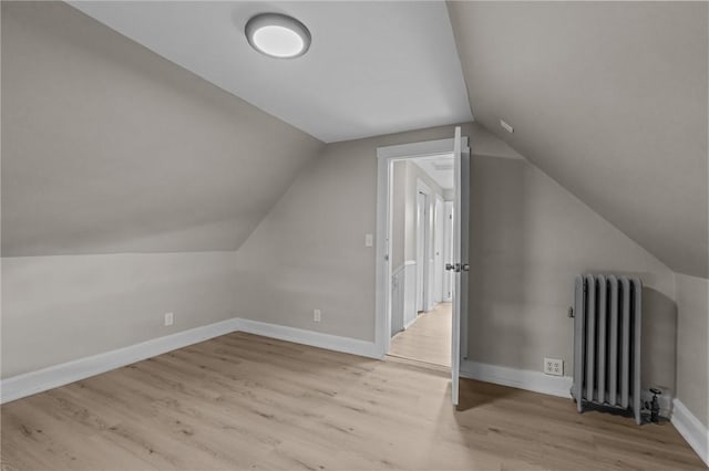 additional living space featuring lofted ceiling, radiator, and light hardwood / wood-style floors