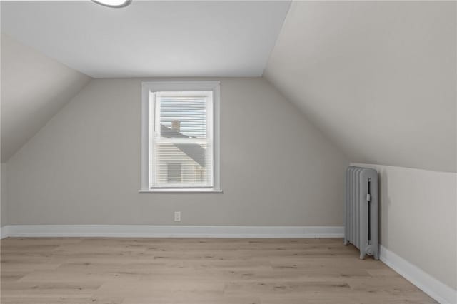 bonus room featuring lofted ceiling, radiator, and light hardwood / wood-style flooring