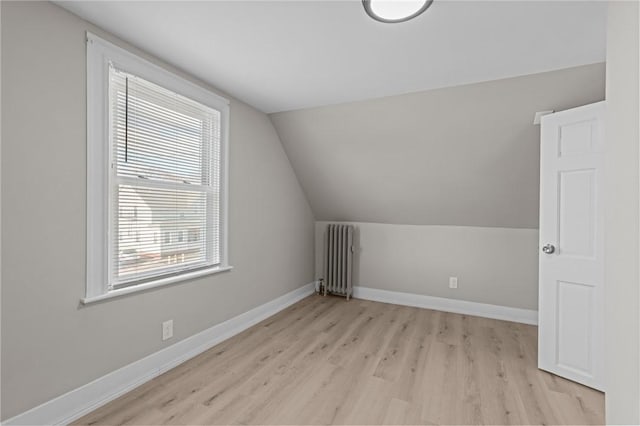 additional living space featuring lofted ceiling, radiator heating unit, and light hardwood / wood-style flooring